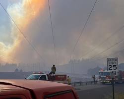 Wildfire smoke and flames surging over the Spokane River during the 2026 Spokane Complex fire crisis.